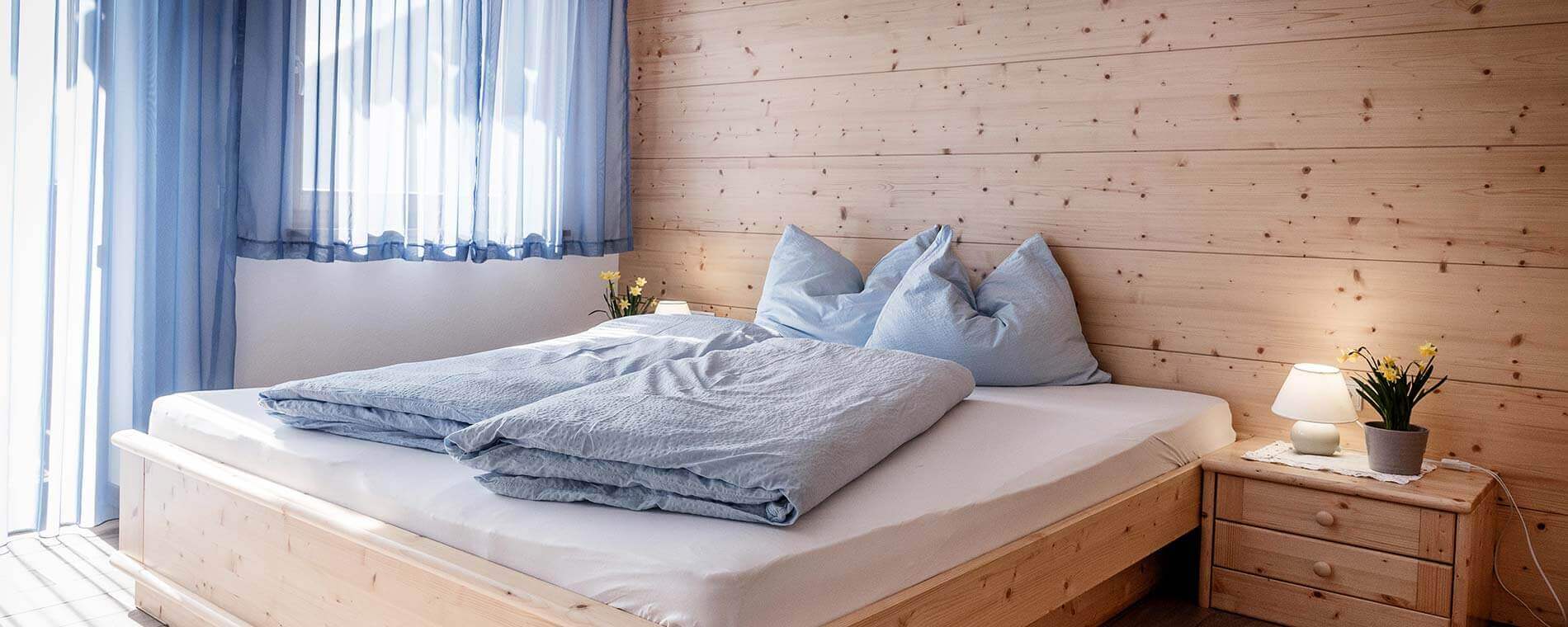 Sonnenstrahlen scheinen auf das helle Doppelbett - Oberhof Weitental