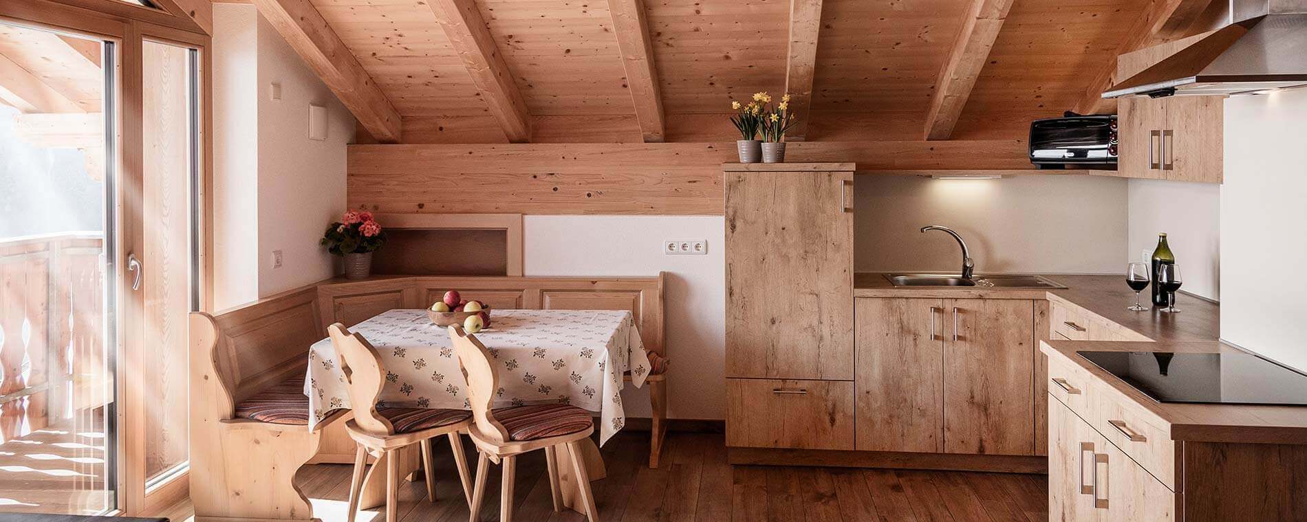 Hölzerne Küche mit Eckbank und Tisch mit einem Obstkorb darauf - Oberhof Weitental